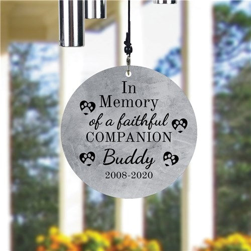 Memorial wind chime for a faithful companion with engraved text in front of a blurred outdoor background.