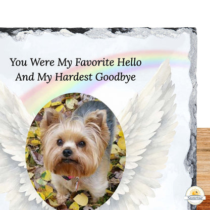 A memorial-style sign or plaque with the text 'You Were My Favorite Hello And My Hardest Goodbye' above a photo of a small Yorkshire Terrier, framed by large white angel wings and a faint rainbow. The product is shown against a white background with a wood surface at the right edge.