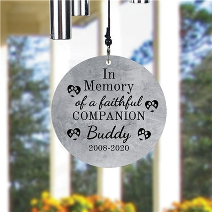 Memorial wind chime for a faithful companion with engraved text in front of a blurred outdoor background.