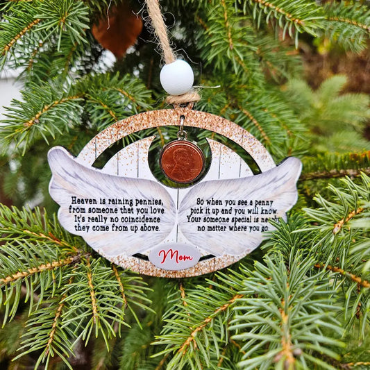 Decorative angel wing ornament with penny and text on a Christmas tree.