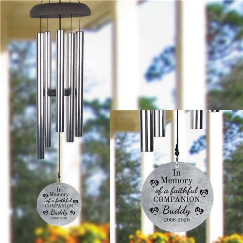 Two wind chimes with engraved messages in a garden setting for pet loss