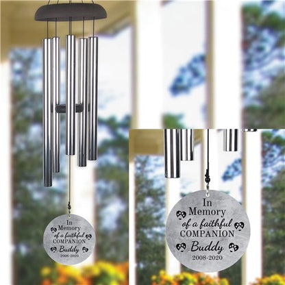Two wind chimes with engraved messages in a garden setting for pet loss